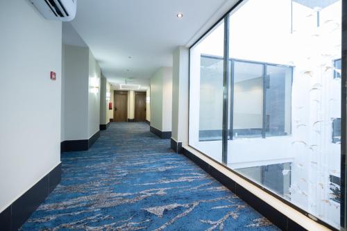 a hallway with a blue carpet and large windows at nasim aizraq hotel فندق نسيم ازرق in Jeddah