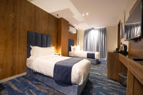 a hotel room with two beds and a flat screen tv at nasim aizraq hotel فندق نسيم ازرق in Jeddah