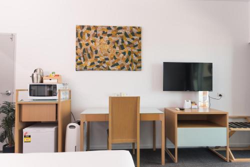 a room with a desk with a computer and a tv at Darwin Harbour Suites in Darwin