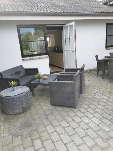 a patio with wicker furniture and a table at Ferielejlighed in Nibe