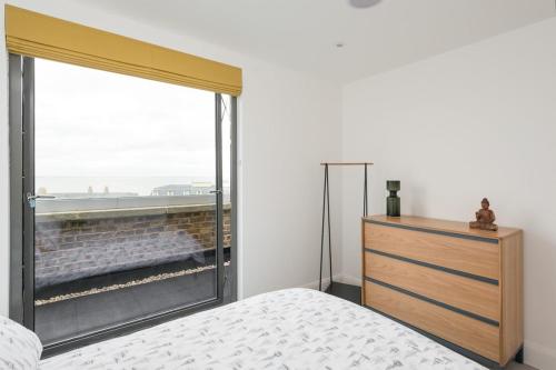 a bedroom with a large window with a bed and a dresser at The Loft Margate in Margate