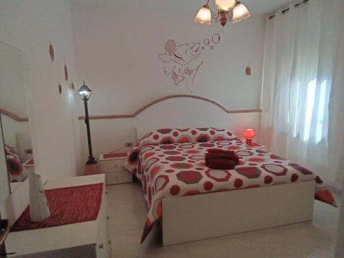 a bedroom with a bed with a red and white comforter at Il Sole Baunei by the sea in Santa Maria Navarrese