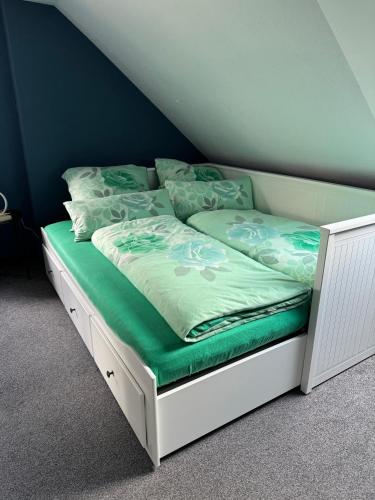 a bed with a white frame and green sheets and pillows at ErzgebirgsLoft in Annaberg-Buchholz