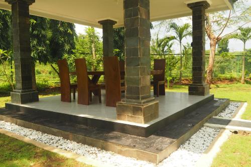 a table and chairs under a pavilion in a garden at The Gecho Inn Country in Jepara
