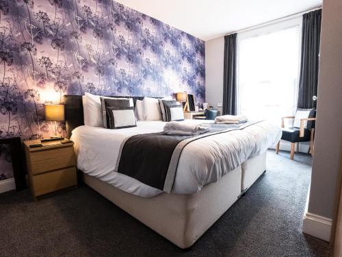 a bedroom with a large bed with a purple wall at Grosvenor House Hotel in Torquay