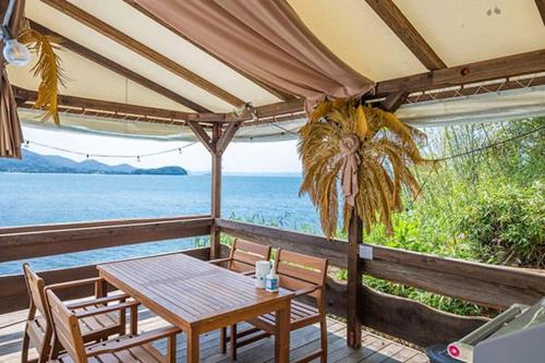 a table and chairs on a porch with a view of the ocean at ITOSHIMA SDGs Village Chikyu MIRAI -海の大パノラマ-全室オーシャンビューのドームテント in Itoshima