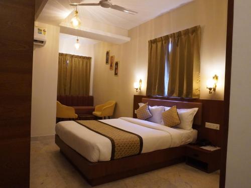 a hotel room with a bed and a chair at Sitevi Inn & Suites in Kota