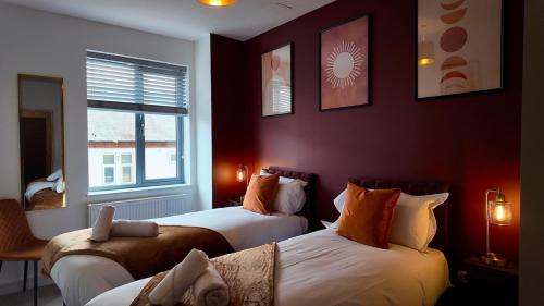 two beds in a room with red walls at City Center 1 Bed Flat in Peterborough