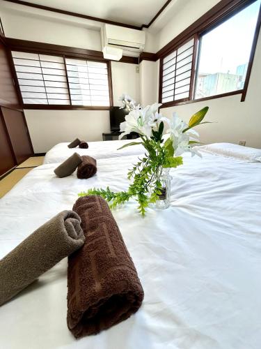 a large white bed with a vase of flowers on it at Ueno Sakura House in Tokyo