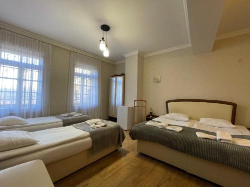 two beds in a room with two windows at Sanuela Boutique Hotel in Tbilisi City