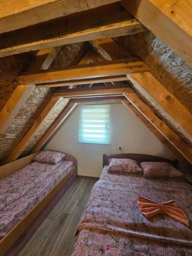 an attic room with two beds and a window at Guest House Ethno Village Milogora in Pluzine