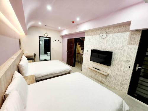 a bedroom with two beds and a tv on a wall at 別有洞天電梯包棟民宿漢北館 in Taitung City