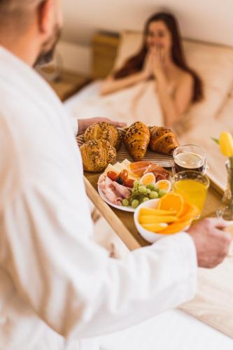 a man sitting in a bath tub with a tray of food at Apartmán Inkognito in Zaječí