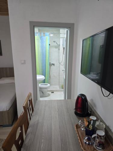a dining room table with a television and a bathroom at Magnolia's Private Room in Gjirokastër