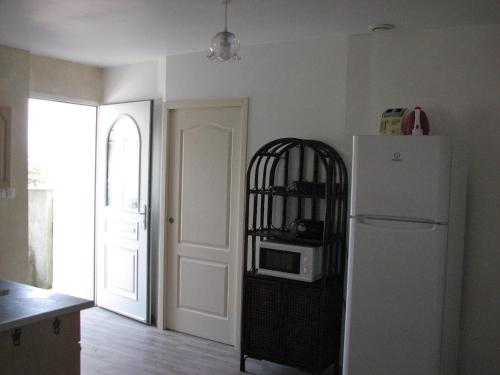 La cuisine est équipée d'un réfrigérateur blanc et d'un four micro-ondes. dans l'établissement Logement Sud Ardèche, à Saint-Sernin