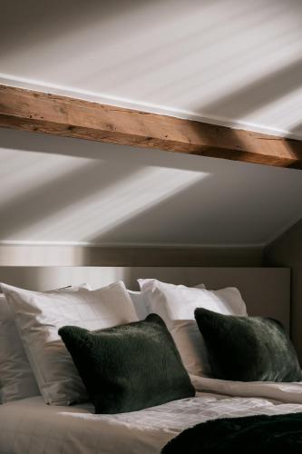 a bed with white pillows and a wooden headboard at Maison Brigida in Noorbeek