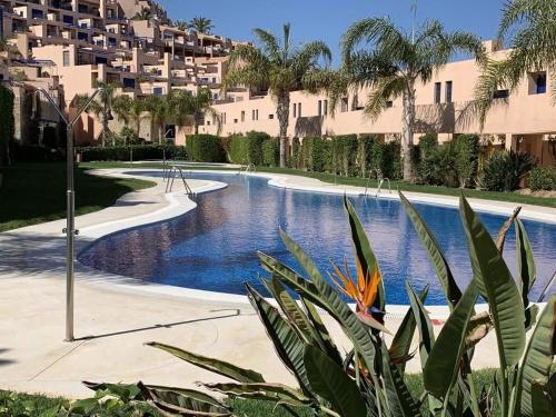 a swimming pool in a resort with palm trees and buildings at Mojacar Playa Atalaya Résidence in Mojácar