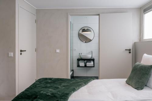 a bedroom with a bed and a mirror and a sink at Maison Brigida in Noorbeek