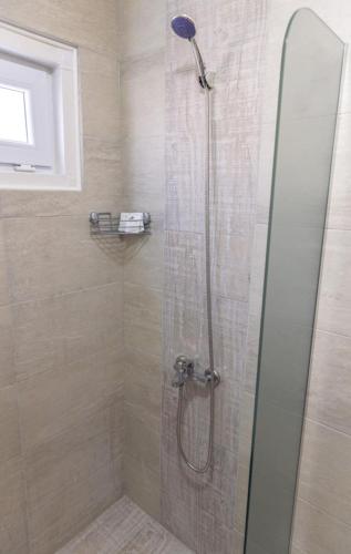 a shower with a glass door in a bathroom at Къщи за гости "Ямира" in Banya