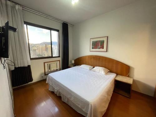 een slaapkamer met een bed en een groot raam bij Apart Hotel Guinard 1403 - Elegante e Acolhedor in Belo Horizonte