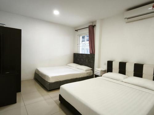 a room with two beds and a window at Miri Homie1-Grd Flr 3 Rooms 12 Pax in Miri