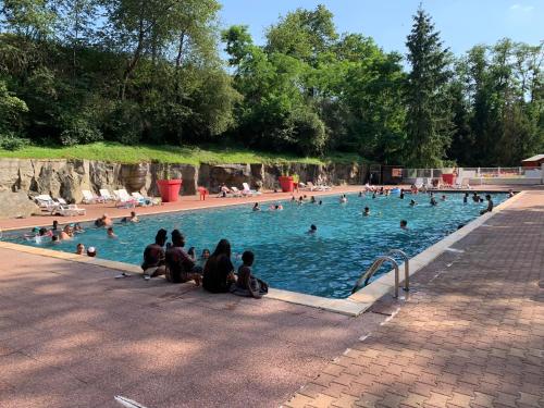 un groupe de personnes assises dans une piscine dans l'établissement Les mobil homes d’oliver rob, à Saint-Chéron