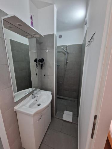 a white bathroom with a sink and a shower at Počitniški dom Portorož / Portoroz Holiday Home in Portorož
