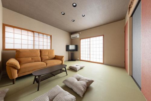 a living room with a couch and two windows at NARU Kanazawa in Kanazawa