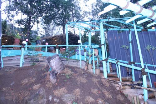 a playground with a blue structure in a garden at Munnar Kudil Resto Cafe in Anaviratty