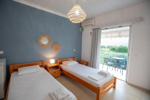 a bedroom with two beds and a balcony at Μπλε Rooms & Apartments in Chiliadou
