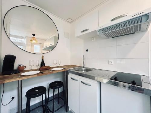 - une cuisine avec des placards blancs, un miroir et des tabourets dans l'établissement Duruy C, studio confortable à deux pas du centre, à Reims