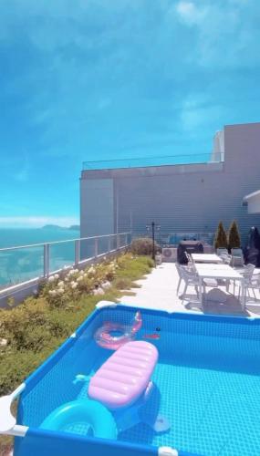 a swimming pool with two pink chairs and a table at 500m2 Busan Ocean view private Let house in Busan