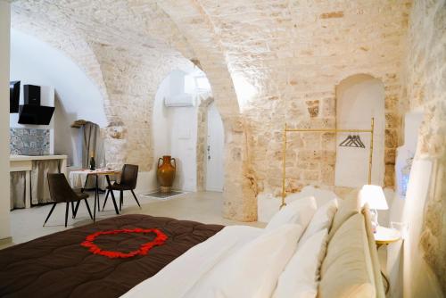 a bedroom with a white couch in a room with a stone wall at Dimora Antica Falegnameria - tra STORIA e RELAX in Ostuni