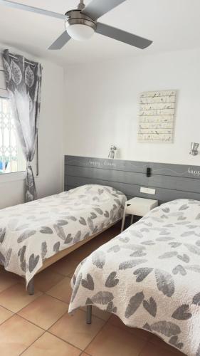 una camera da letto con due letti e un ventilatore a soffitto di Casa ANNA - clim,2 chambres, 50 m plage, terrasse 16m2, Wifi a Platja  d'Aro