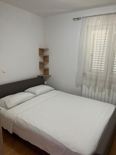 a white bed in a bedroom with a window at Apartments Vido in Vodice