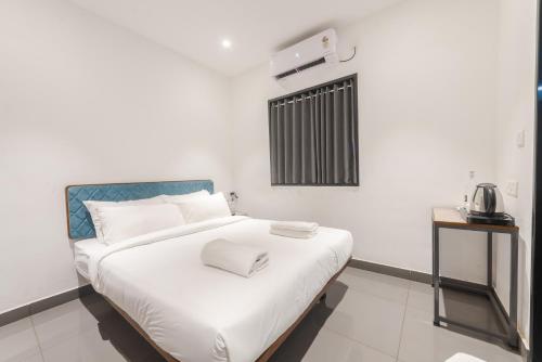 a bedroom with a bed with white sheets and a window at Shoolin Palace in Mangalore