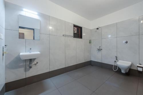 a bathroom with a sink and a toilet at Shoolin Palace in Mangalore