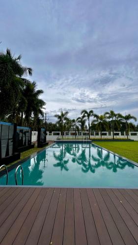 a large swimming pool with a wooden deck and palm trees at Shoolin Palace in Mangalore