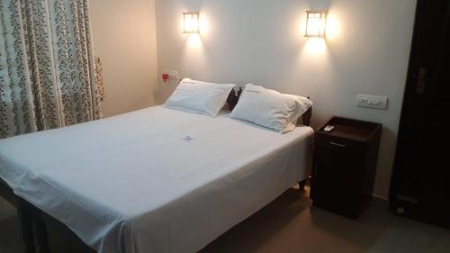 a white bed with two pillows and a night stand at Philips Homestay in Alleppey