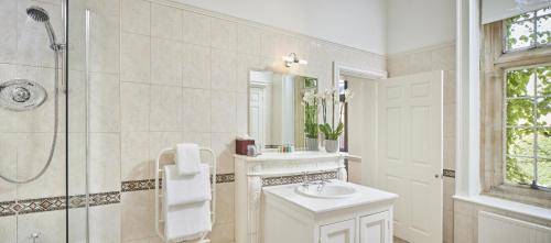 a white bathroom with a sink and a shower at Tylney Hall Hotel in Hook