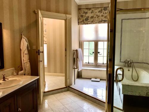a bathroom with a tub and a sink and a shower at Tylney Hall Hotel in Hook