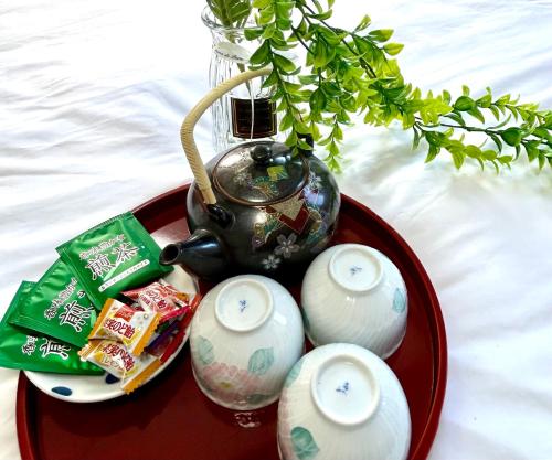 - un plateau rouge avec des bougies et un vase avec une plante dans l'établissement Ueno Sakura House, à Tokyo