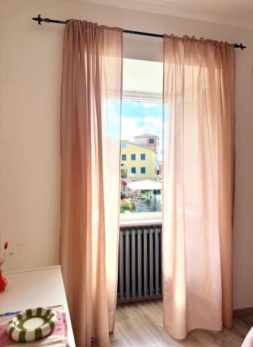 a room with a window with curtains and a table at Appartamento in pieno centro - La Piazzetta in Passignano sul Trasimeno