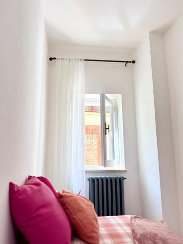 a bedroom with a bed with pink pillows and a window at Appartamento in pieno centro - La Piazzetta in Passignano sul Trasimeno