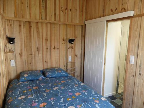 une chambre avec un lit et un mur en bois dans l'établissement Château d'Oléron La Maison Bleue, au Château-dʼOléron