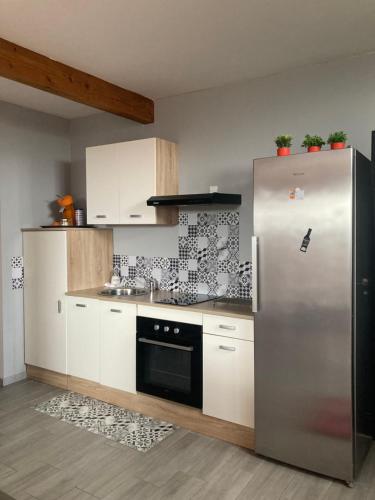 une cuisine avec un réfrigérateur en acier inoxydable et des armoires blanches dans l'établissement La Maison de Valie, à Mercoeur