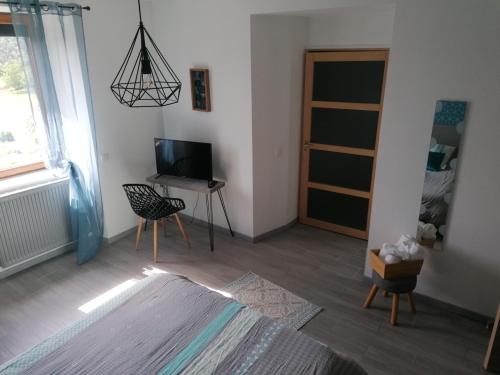 a living room with a television and a table with a chair at La Maison de Valie in Mercoeur