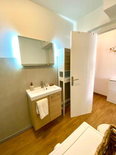 La salle de bains est pourvue d'un lavabo et d'une porte blanche. dans l'établissement Charming Flat close to palais des festivals, au Cannet