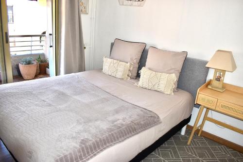 - une chambre avec un grand lit, des oreillers et une table dans l'établissement Charming Flat close to palais des festivals, au Cannet