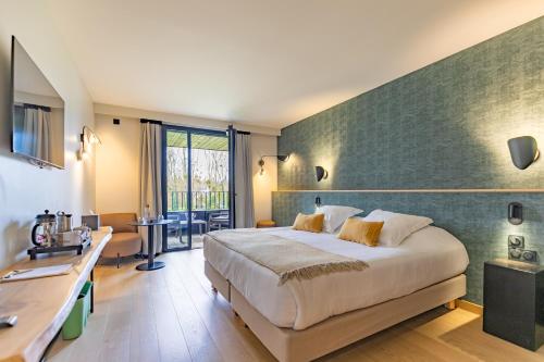 a hotel room with a large bed and a desk at Auberge de la Caillère in Candé-sur-Beuvron